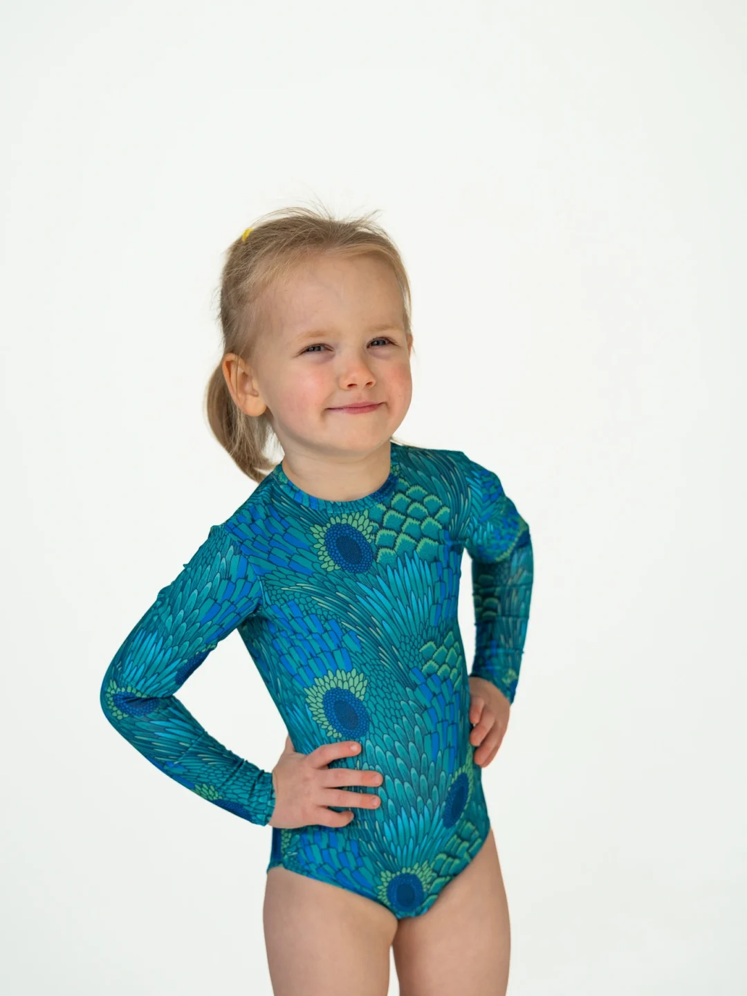 Children's long-sleeve tan-through one-piece swimsuit in teal peacock feather print, front view
