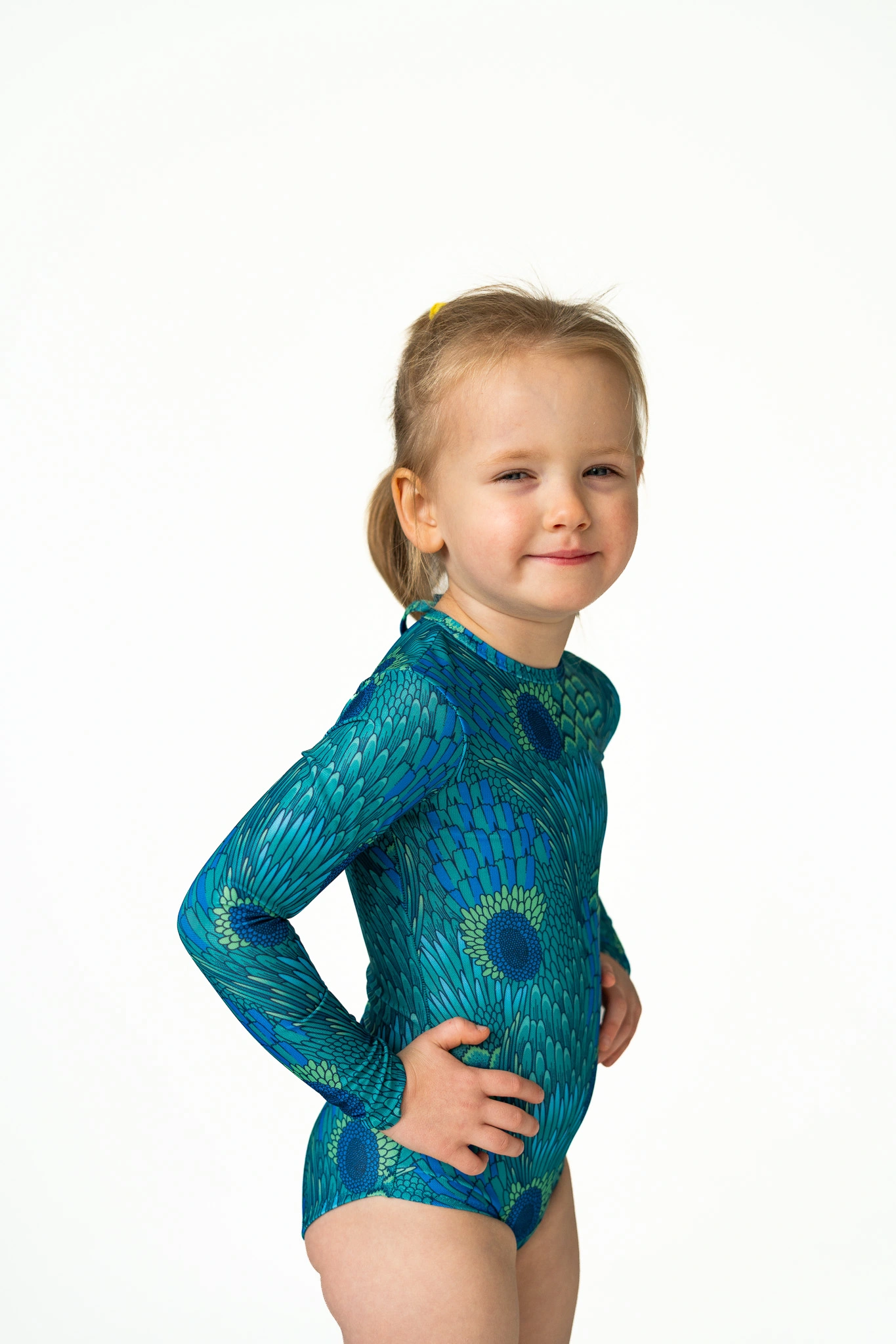 Z20 Peacock Children's long-sleeve tan-through one-piece swimsuit in teal peacock feather print, side view
