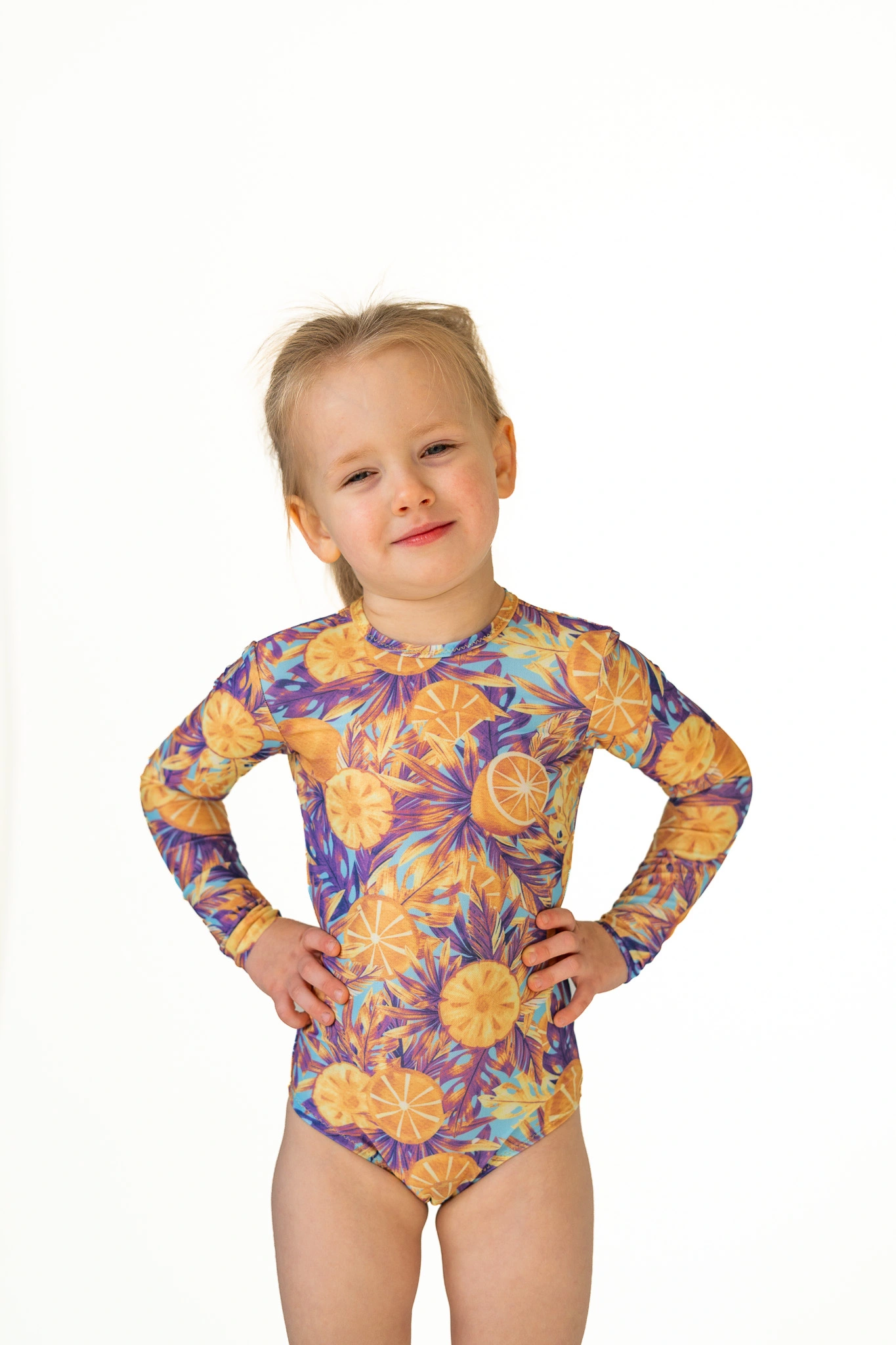 Z20 Peacock Children's long-sleeve tan-through one-piece swimsuit in orange and purple floral print, front view