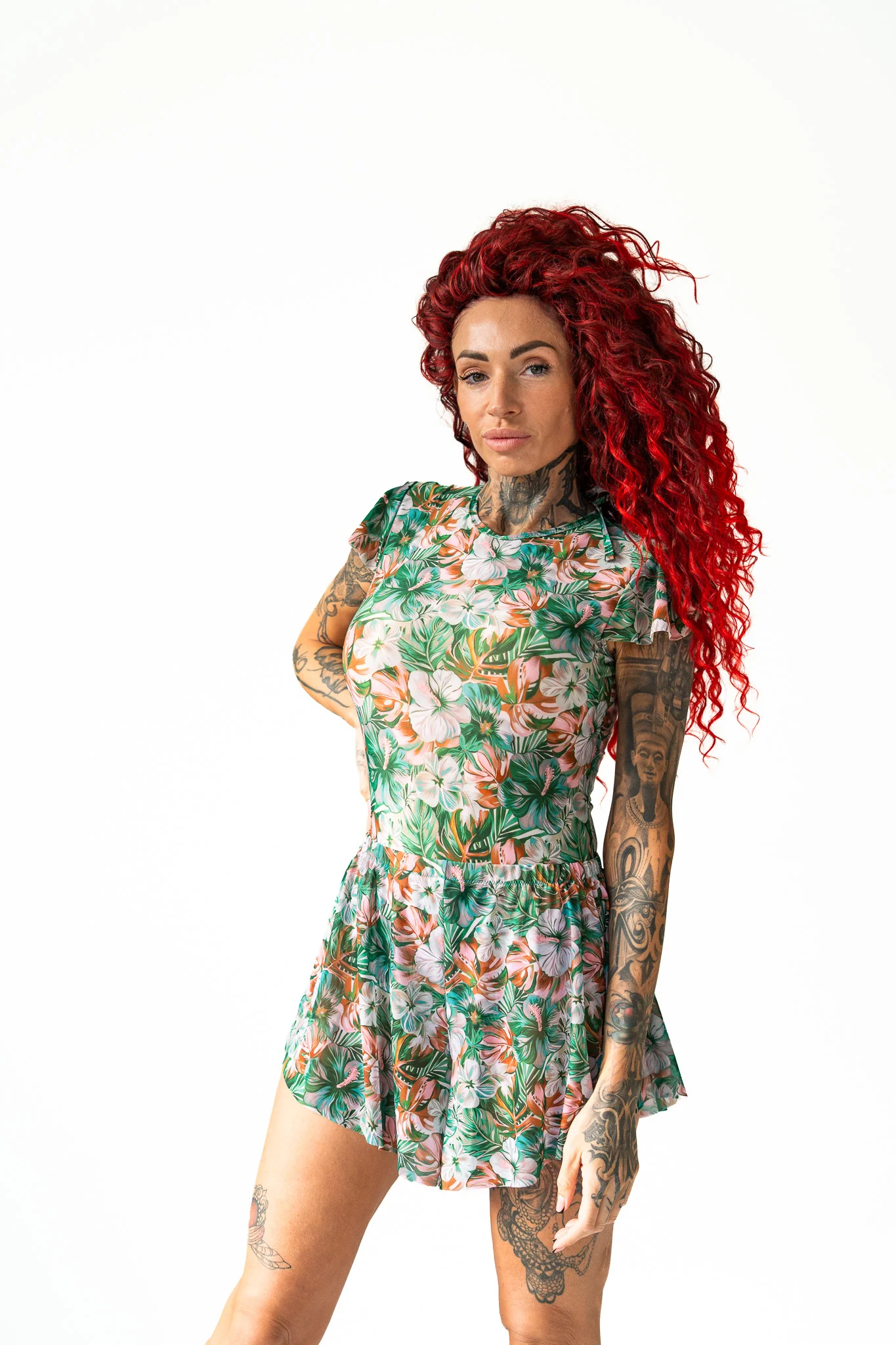 Tattooed woman with red curly hair posing in a green floral print matching set Tattooed woman with red curly hair posing in a green floral print matching set